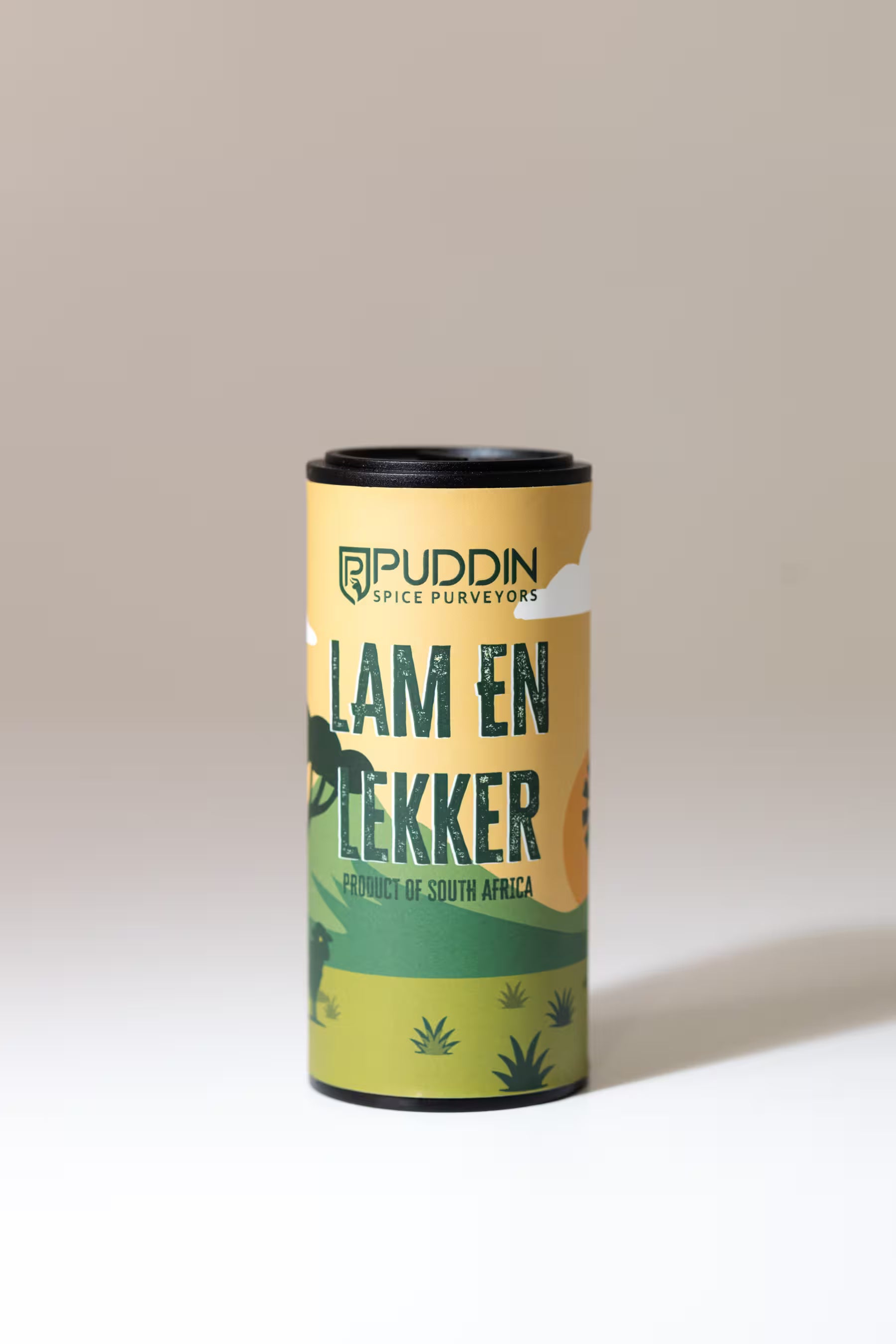 A cylindrical canister of Puddin Spice Surveyors 'Lam En Lekker' seasoning, featuring a yellow and green label with a black lid, set against a neutral beige background.